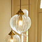 Close-up of a ribbed glass pendant light with a brass fitting and warm glow.