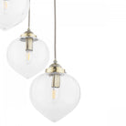 Close-up of two clear glass pendant lights with brass fittings.