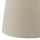 A close-up of the bottom right side of a beige lampshade.