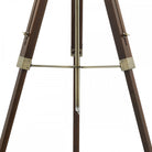 Close-up of the dark wood tripod lamp's legs with brass accents and a central rod.