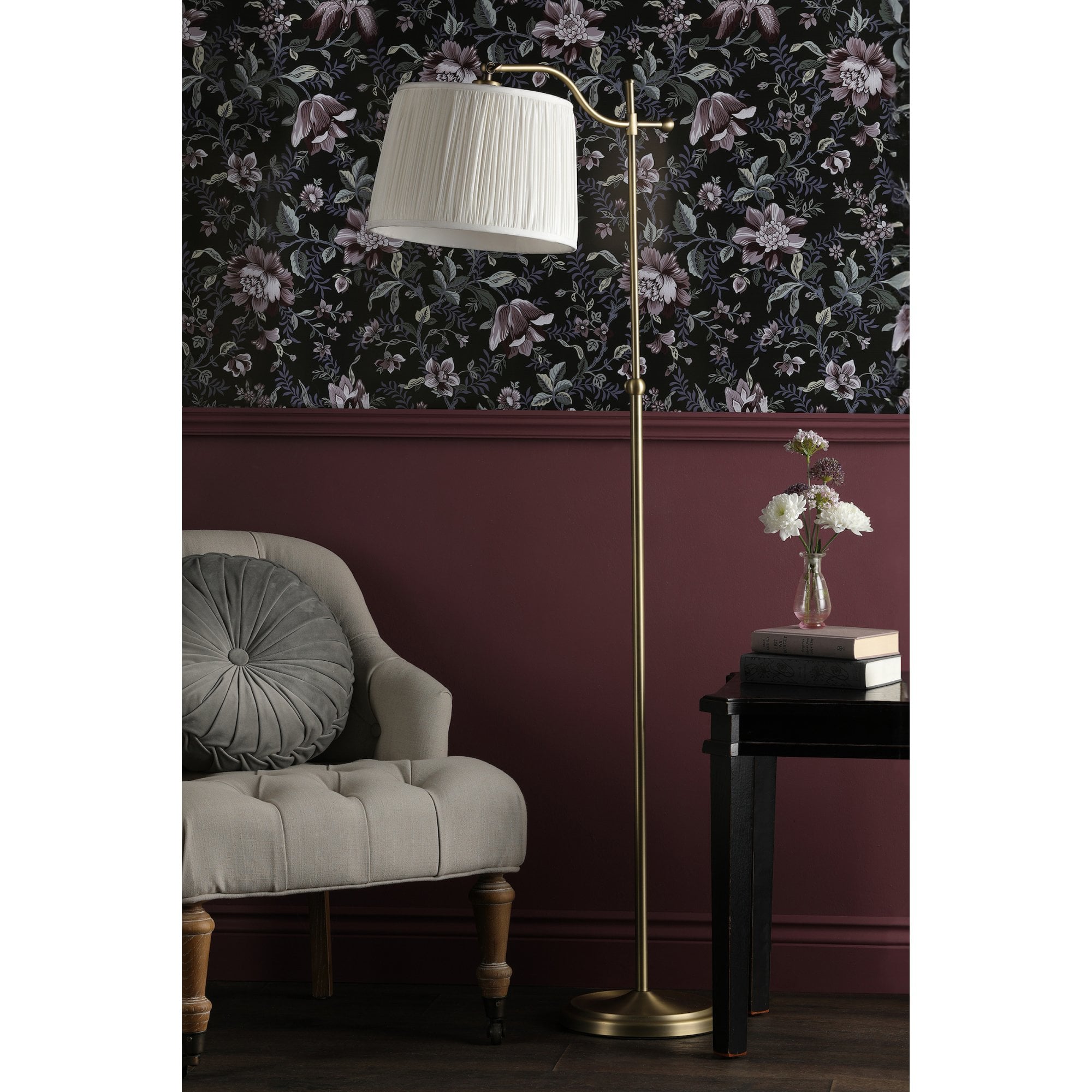 A brass floor lamp with a pleated shade positioned in a cozy reading nook.