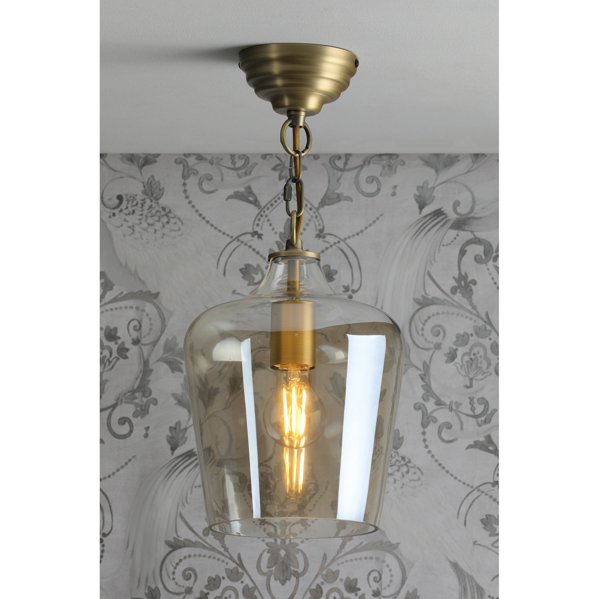 A full view of the pendant light hanging, with the bulb illuminated.