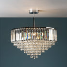 A sparkling crystal chandelier hangs from a ceiling, illuminating a dark blue wall.