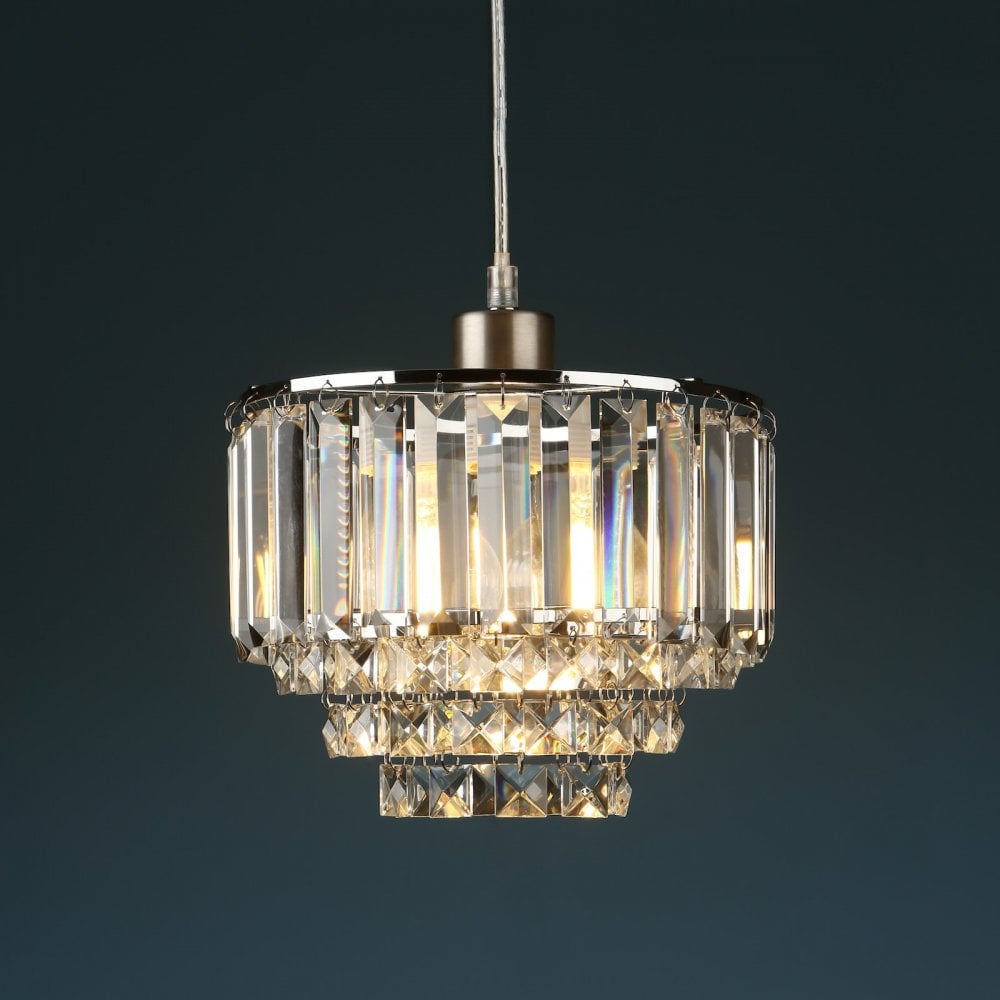 Tiered crystal pendant light, illuminated with warm light against a dark background.