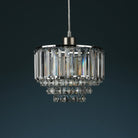 Tiered crystal pendant light, unilluminated, against a dark blue-grey background.