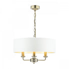 A brass three-arm pendant light with a white drum shade against a white background.