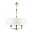 A brass three-arm pendant light with a white drum shade against a white background.