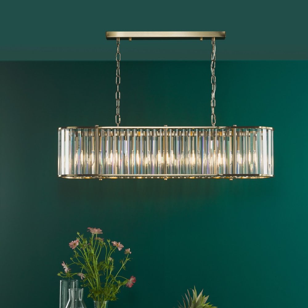 An illuminated rectangular chandelier with a gold frame hanging above a table with flowers.