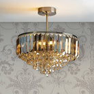 A sparkling chandelier with gold and clear crystals hangs from a decorative ceiling.