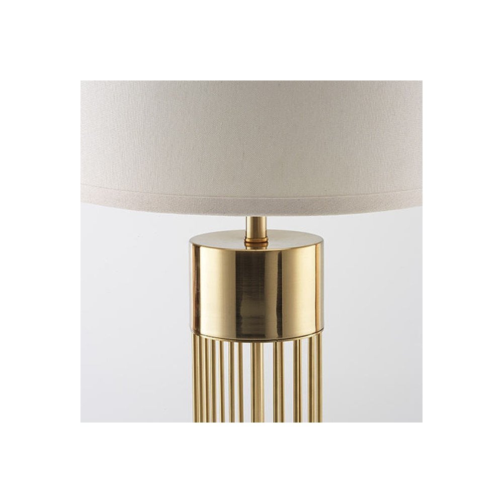 A close-up of the lamp's gold base with detailed vertical ribs and white shade.