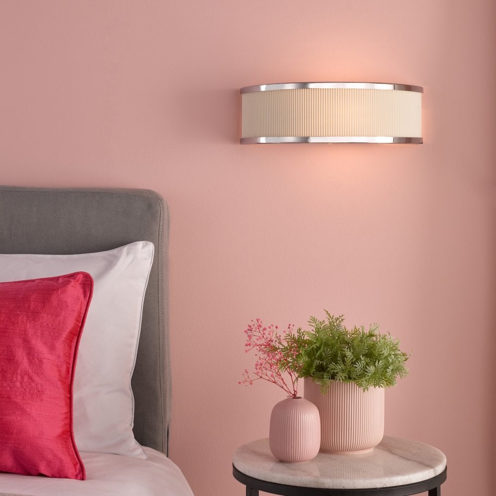 Subtle bedside lighting from an elegant wall sconce illuminates a blush pink room.