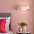 Subtle bedside lighting from an elegant wall sconce illuminates a blush pink room.