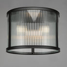 A close up view of a ceiling mounted cylindrical light with fluted glass and a black frame.