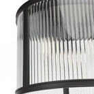 A close up view of a ceiling mounted cylindrical light with fluted glass and a black frame.