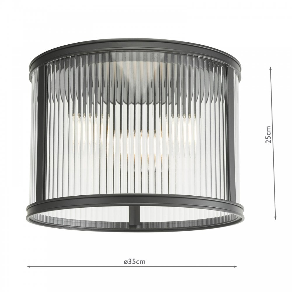 A close up view of a ceiling mounted cylindrical light with fluted glass and a black frame.