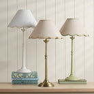 Three elegant table lamps with scalloped shades and varying bases, providing soft lighting.