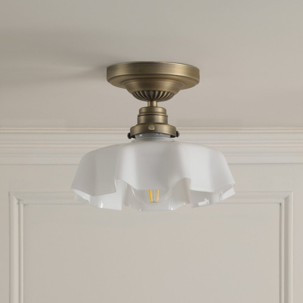 A brass ceiling light with a ruffled, translucent glass shade on a light ceiling.