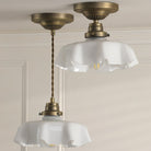 Two brass lights with ruffled translucent glass shades, one a ceiling light and one a pendant.