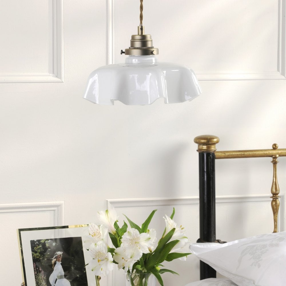 A vintage-style white fluted glass pendant light hangs above a bedside table.