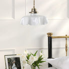 A vintage-style white fluted glass pendant light hangs above a bedside table.
