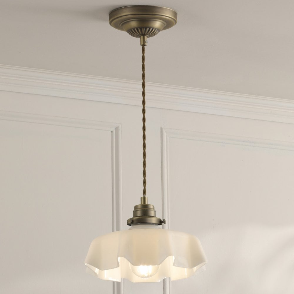 A brass pendant light with a fluted white glass shade hanging from the ceiling.