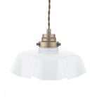 A close-up of a fluted white glass pendant light with brass accents.