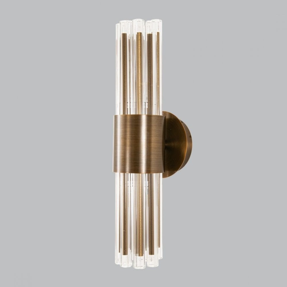 A modern brass wall sconce with clear glass rods, providing elegant, vertical lighting.