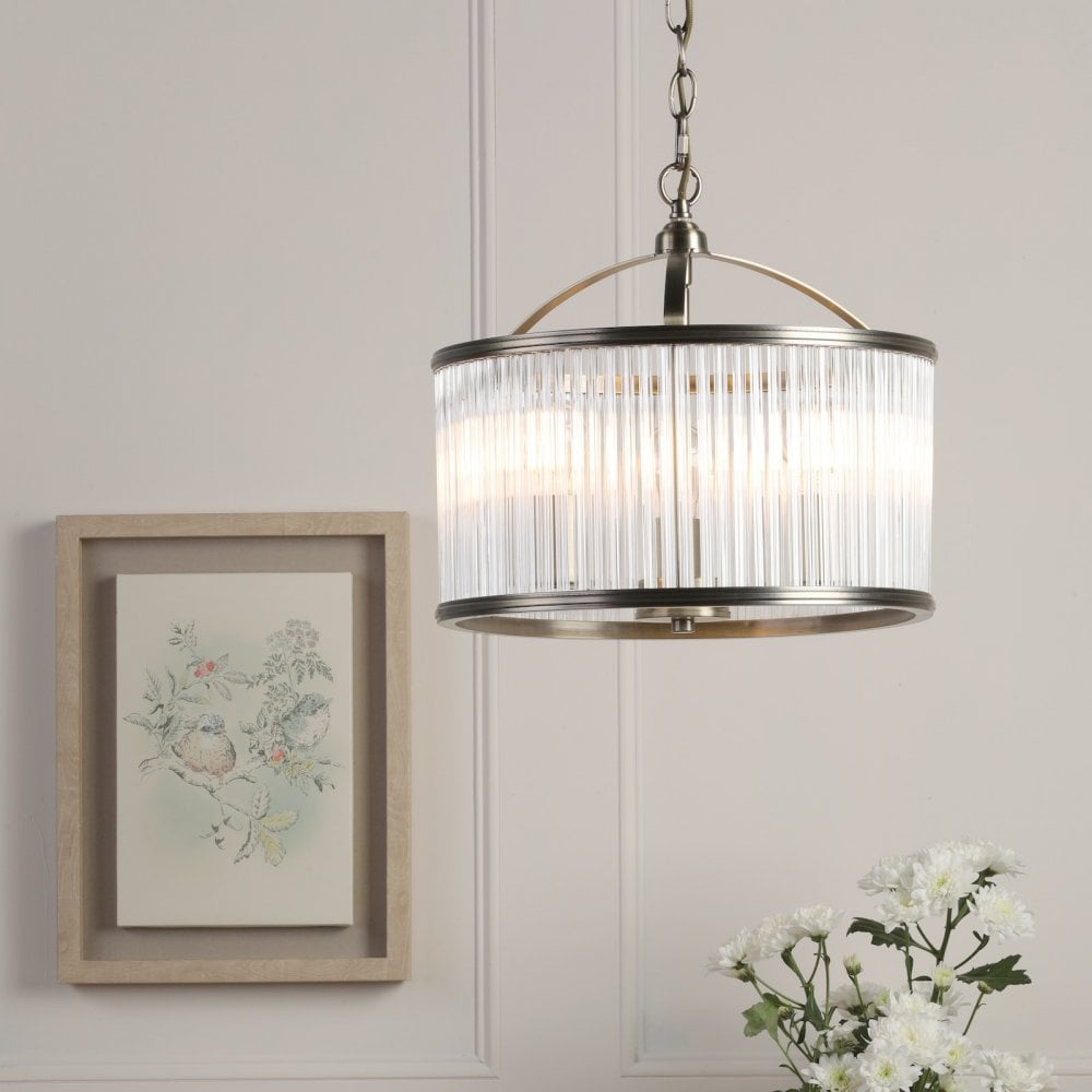 A round, antique brass and clear reeded glass pendant light illuminates a bright room.