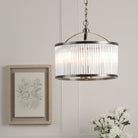 A round, antique brass and clear reeded glass pendant light illuminates a bright room.