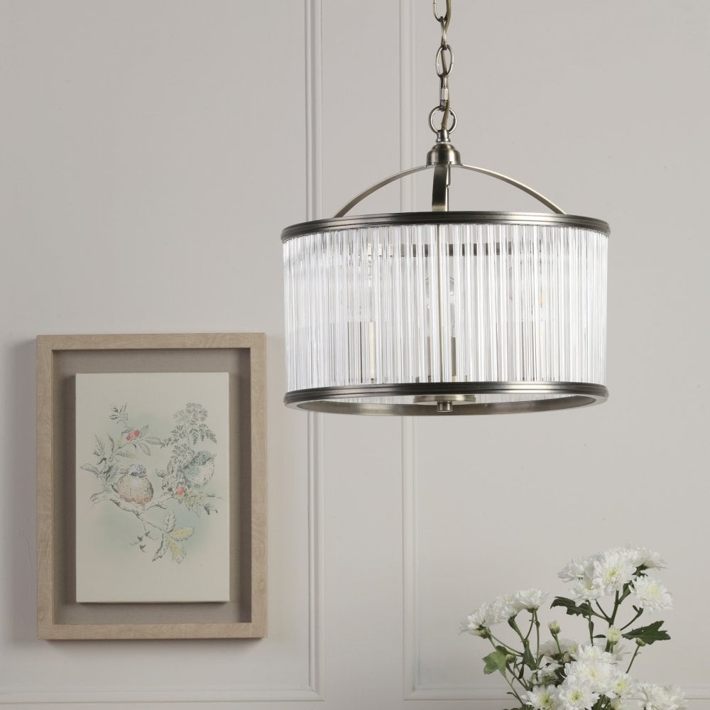 A round, antique brass and clear reeded glass pendant light hangs in a well-lit room.