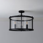 A stylish semi-flush ceiling light in black finish, featuring a clear glass drum and three bulbs.