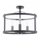 A contemporary black semi-flush light fixture with a clear glass drum, housing three exposed bulbs.