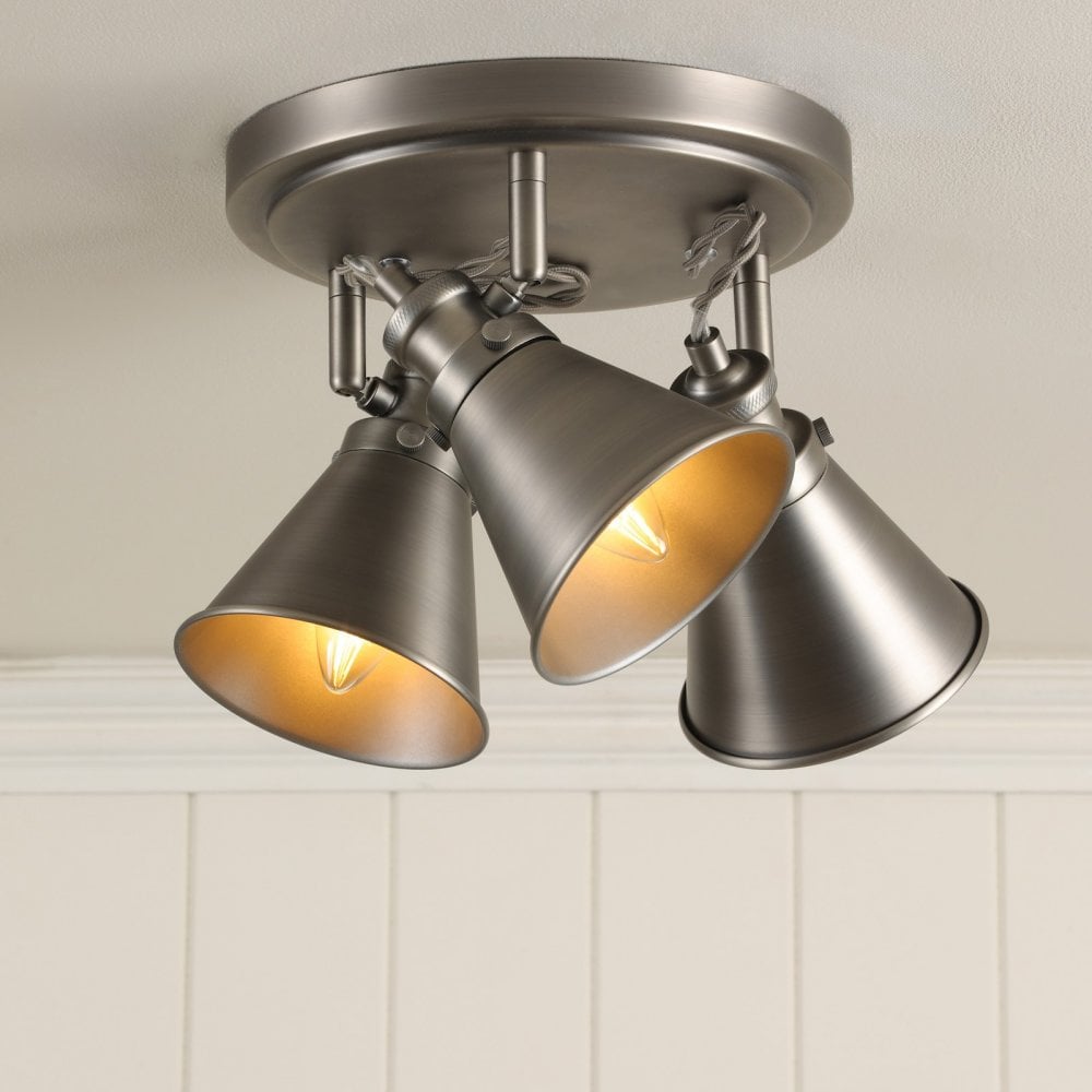A three-bulb industrial-style ceiling light with warm light emanating from each.