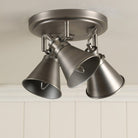 A three-bulb industrial-style ceiling light with no light emanating from each.