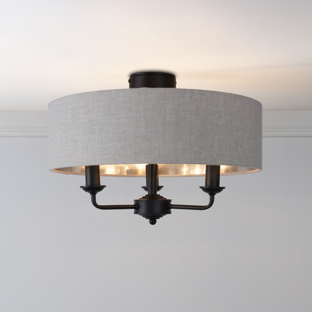A semi-flush mount ceiling light with a grey fabric drum shade and three exposed black bulbs.