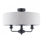 A semi-flush mount ceiling light with a grey fabric drum shade and three exposed black bulbs.