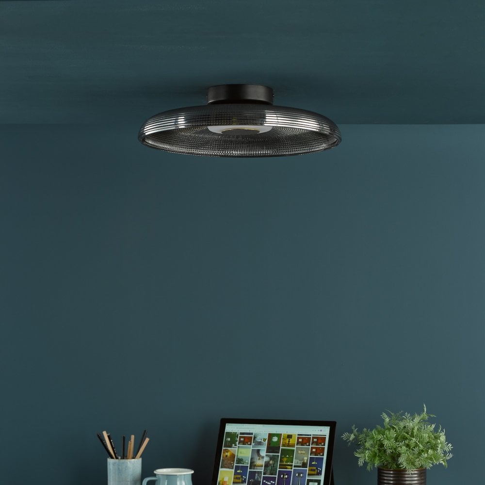 A minimalist ceiling light with a dark gray glass shade is installed in a dark blue room.