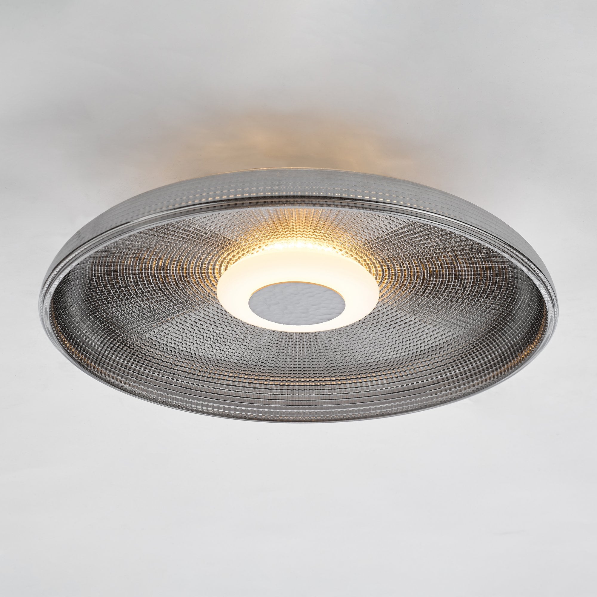 A close-up view of the minimalist ceiling light, showcasing its textured glass and soft glow.