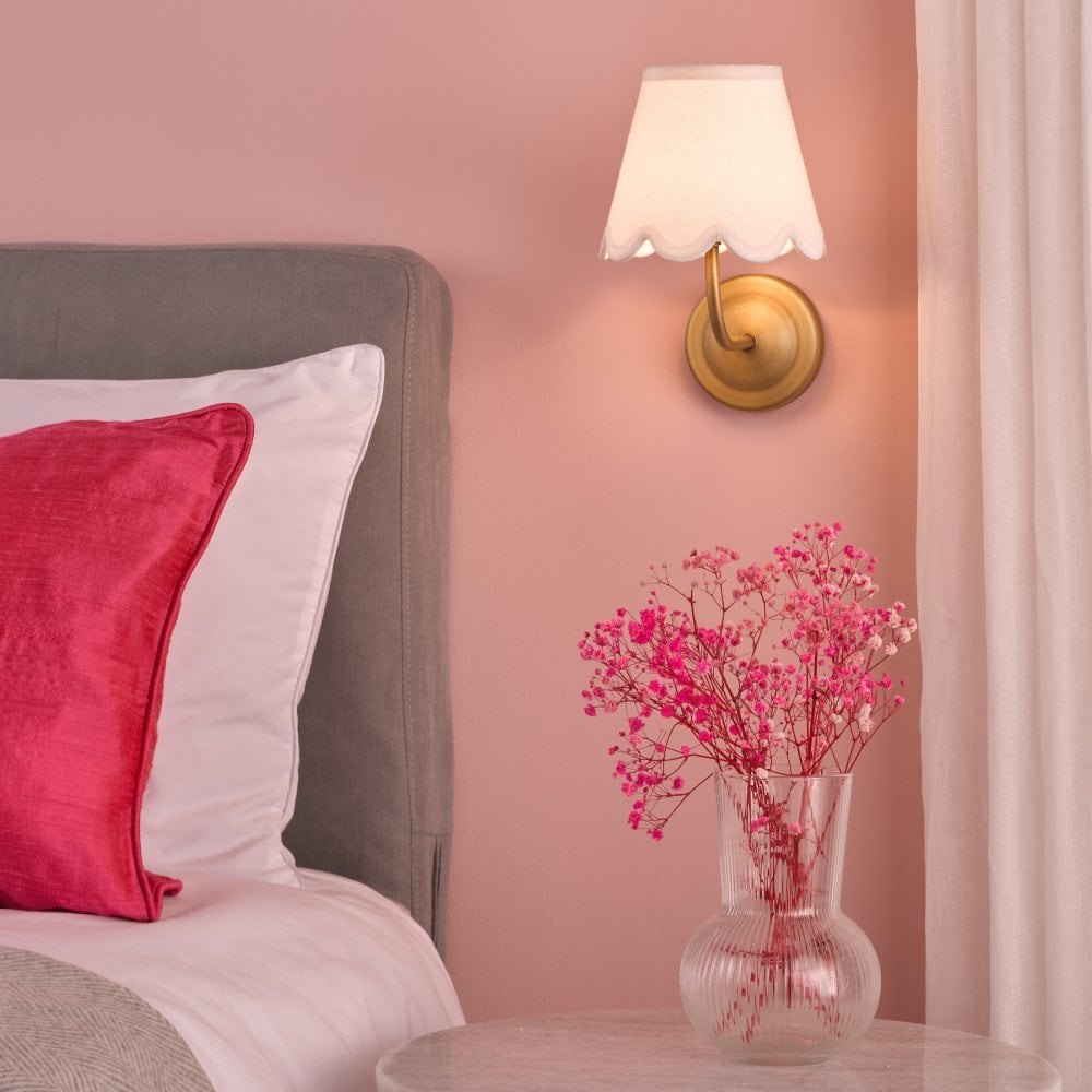 Scalloped wall sconce in a pink bedroom, providing soft light.