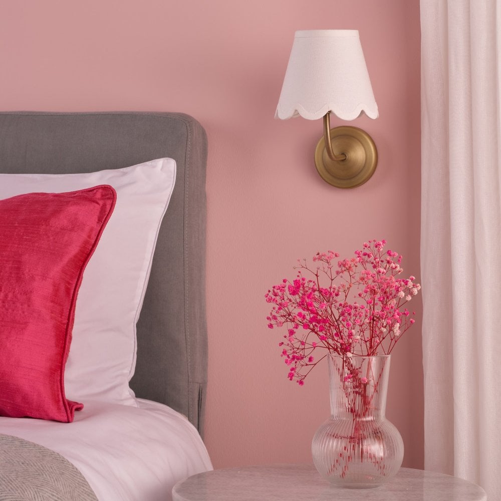 Scalloped wall sconce in a pink bedroom, providing soft light.
