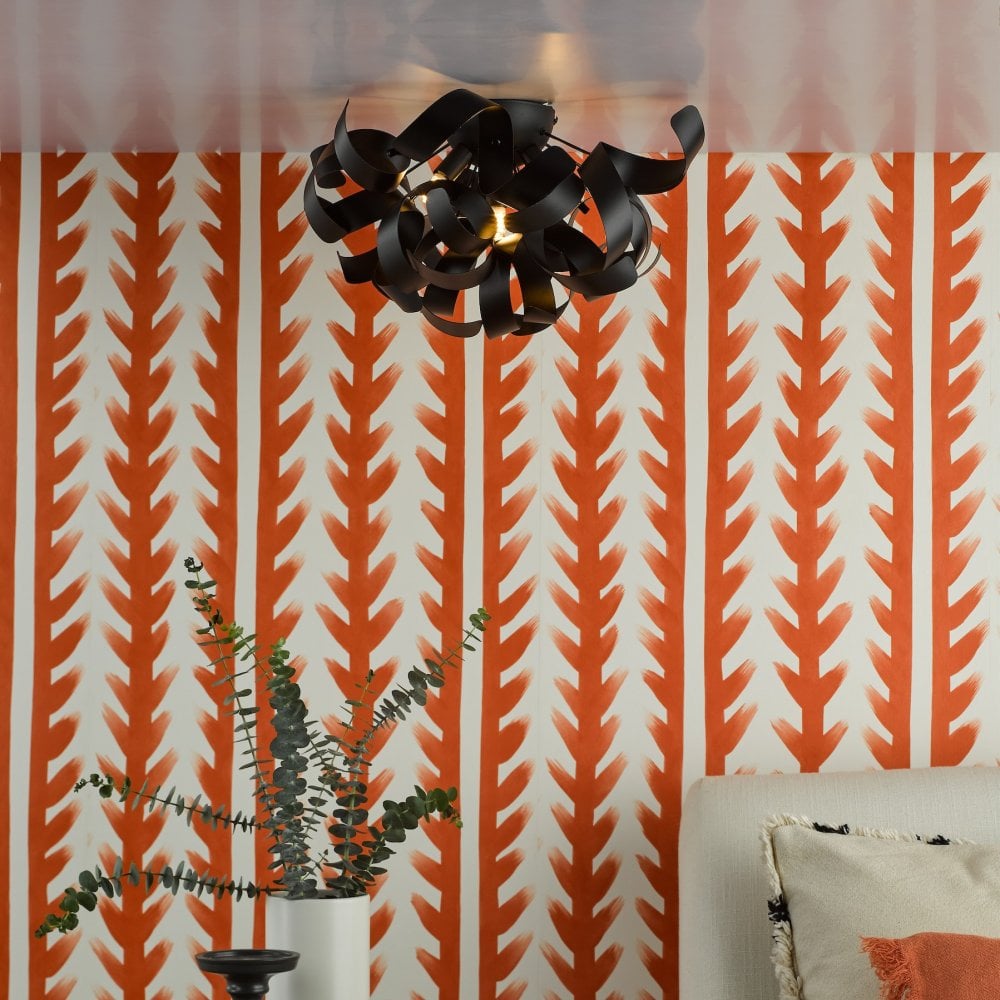 A black ceiling light with abstract metal curls illuminates a room with orange and white striped wallpaper.