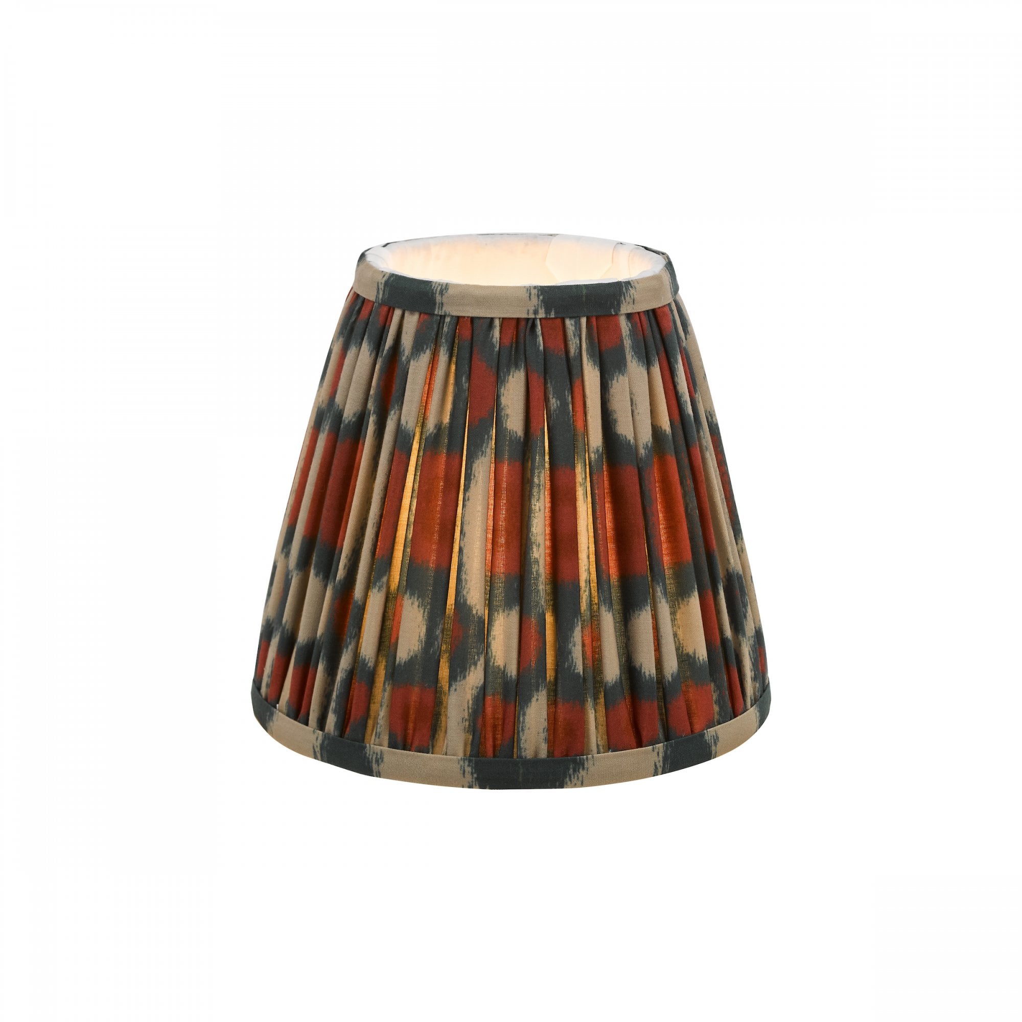 Pleated ikat lampshade in rust and gray with a white interior, lit from within.