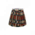 Pleated ikat lampshade in rust and gray with a neutral trim.