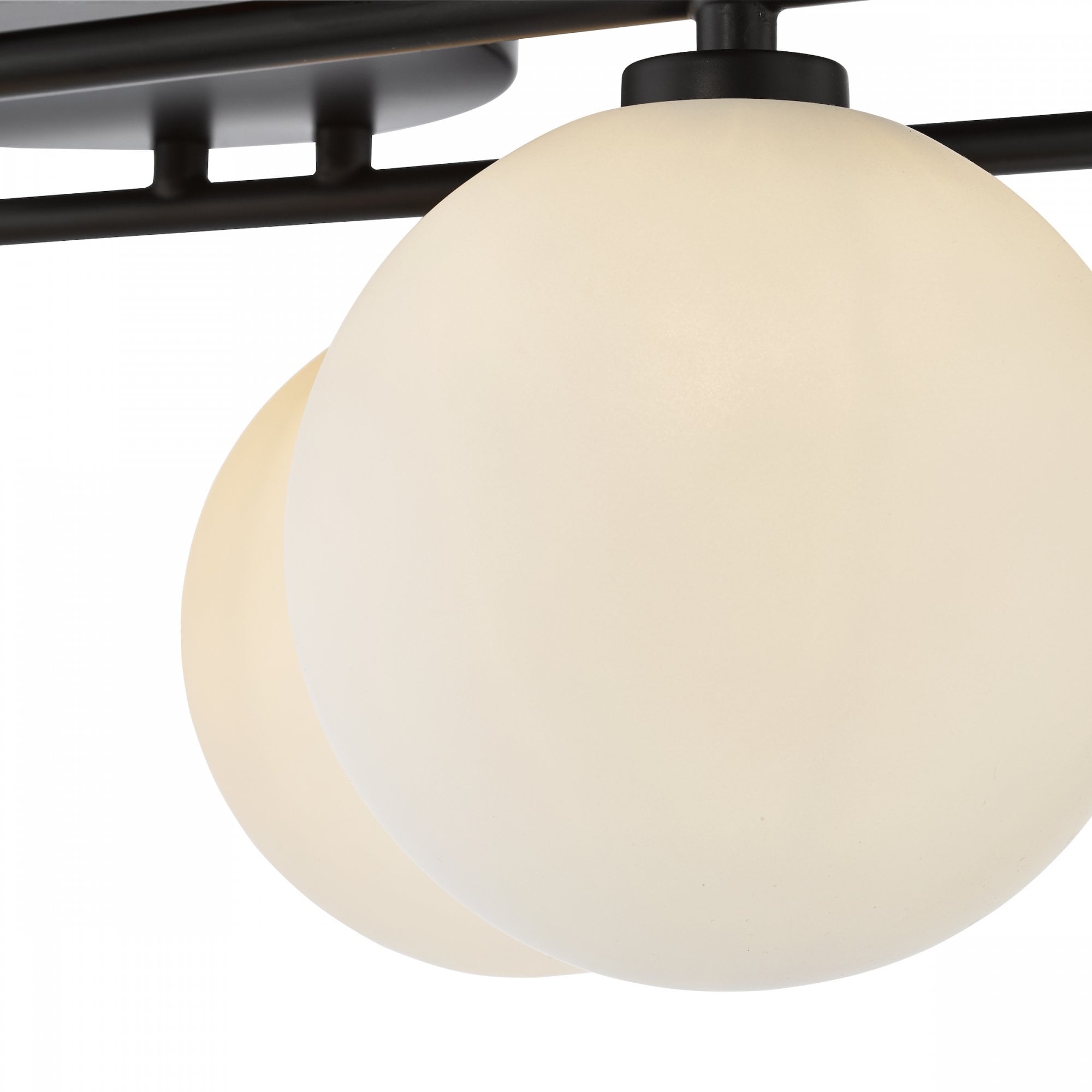 A close-up of two opaque white globe lights with black fittings.