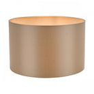 A sleek, cylindrical lampshade in a warm, muted gold color with a light interior.
