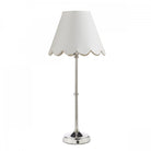 A polished nickel table lamp with a white scalloped lampshade against a white background.