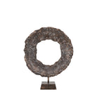 A rustic, bronze-colored metal ring sculpture on a square base against a white background.