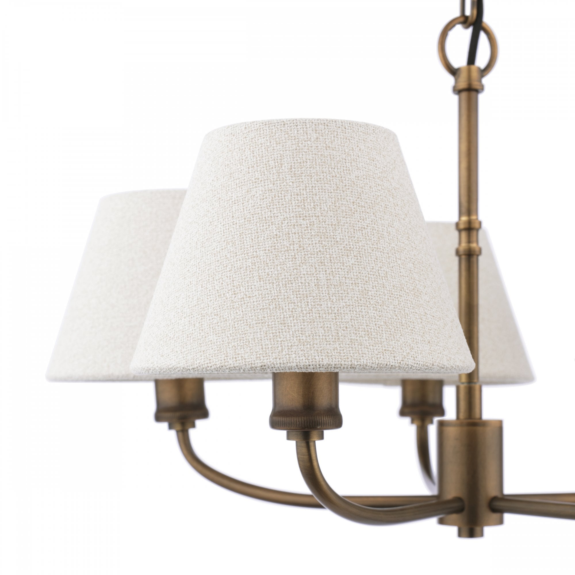 Close-up of the textured off-white shades and antique brass finish of a chandelier.