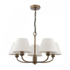A five-light chandelier with textured off-white shades and an antique brass finish.