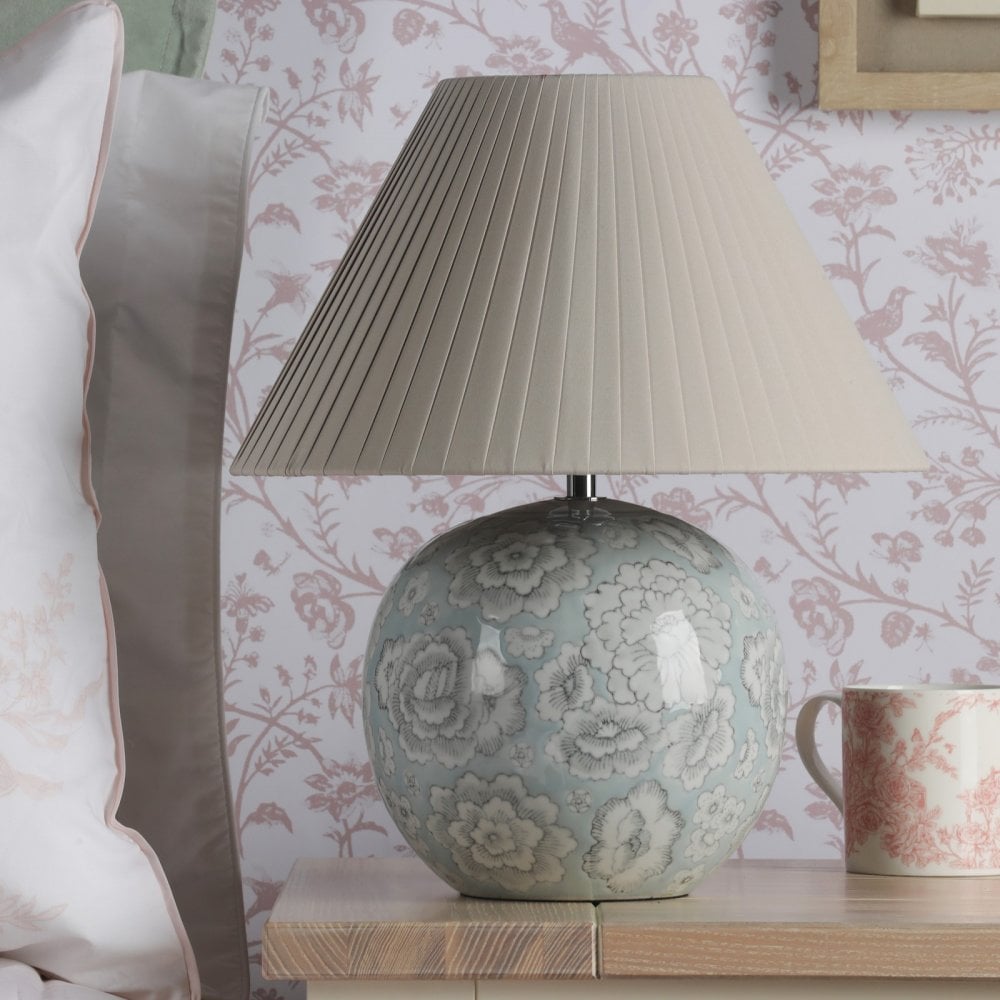 A floral globe lamp sits on a wooden nightstand, adding warmth to a bedroom.